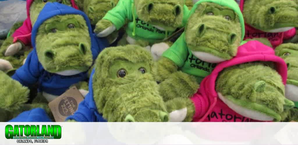A group of green plush alligator toys wearing colorful hoodies.