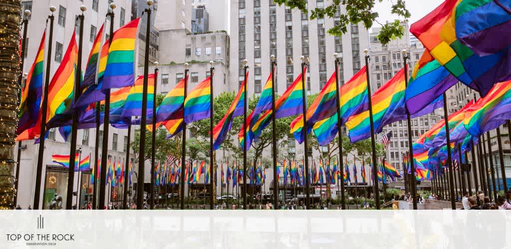 Rows of rainbow flags at Rockefeller Plaza with tall buildings in the background.