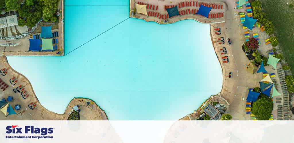 Aerial view of a large swimming pool with surrounding lounge chairs and canopy tents at Six Flags.