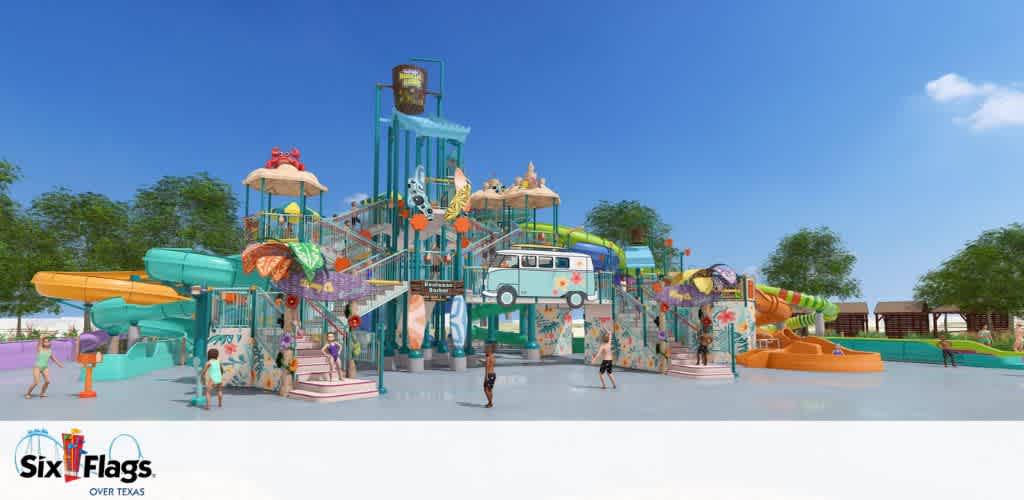 Colorful water park structure with slides, stairs, and themed decorations under a clear blue sky. Children are playing around the area, enjoying the vibrant attractions. Trees and cabanas are visible in the background, enhancing the lively and fun atmosphere. The Six Flags Over Texas logo is in the lower-left corner.