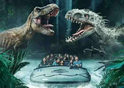 A thrilling theme park ride features visitors on a raft as they face two large dinosaurs with open jaws in a jungle setting. The scene captures excitement and adventure as the group navigates through the water surrounded by lush greenery and waterfalls, creating an immersive prehistoric experience.