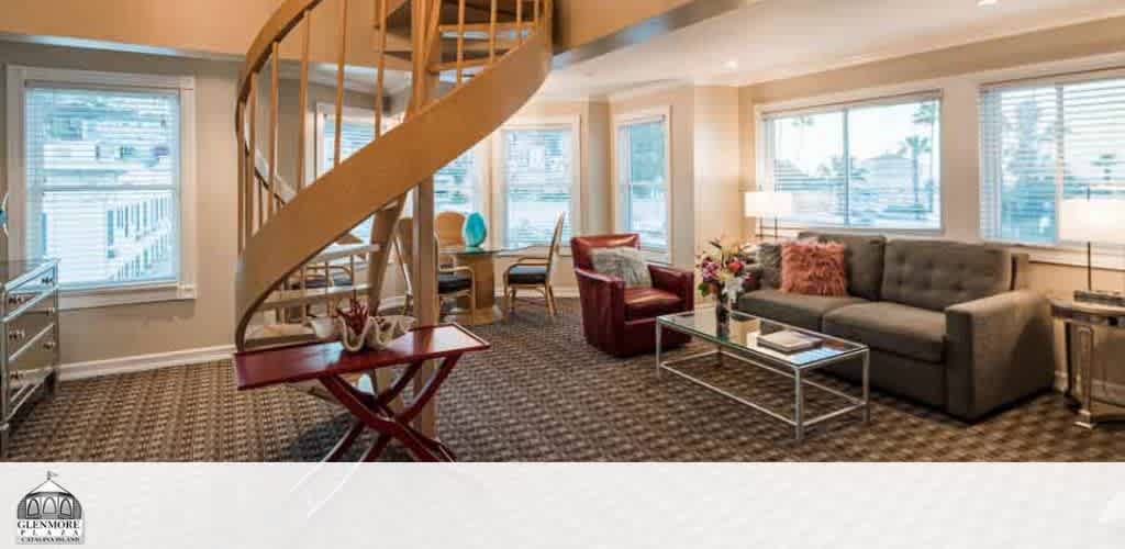 Living area with spiral staircase, gray sofa, and large windows.