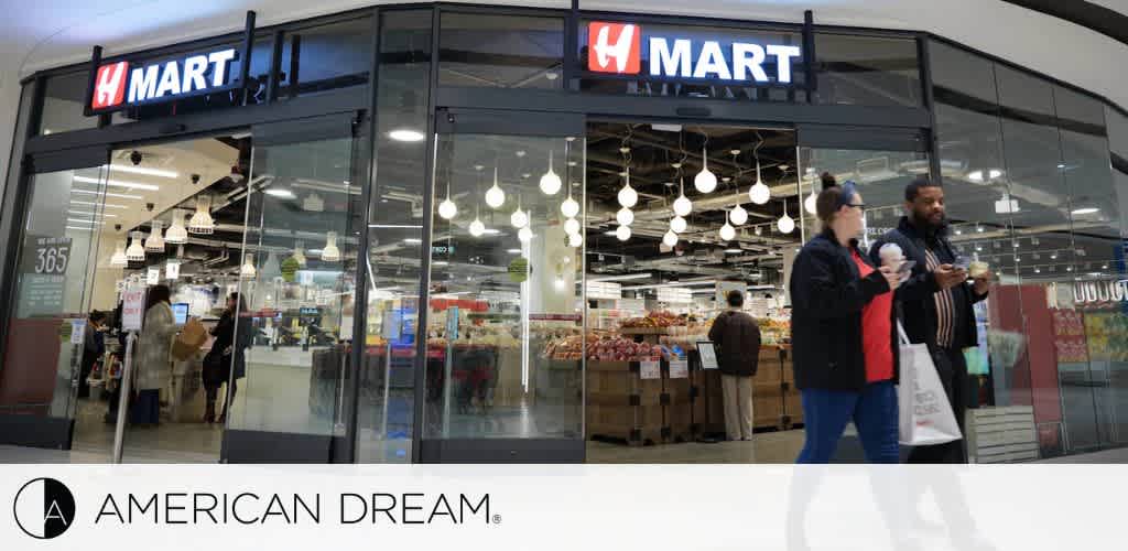 H Mart store entrance in a shopping center with people walking by, featuring the American Dream logo.