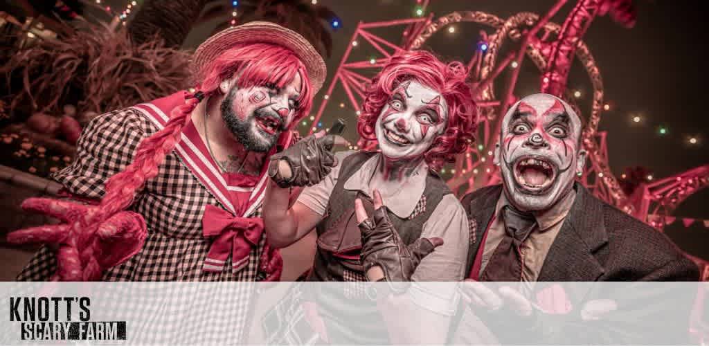 Three people dressed as clowns with creepy makeup in an amusement park setting.