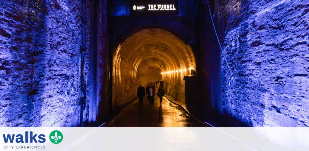 People walking through a lit tunnel with blue and yellow lighting on stone walls at funex.com