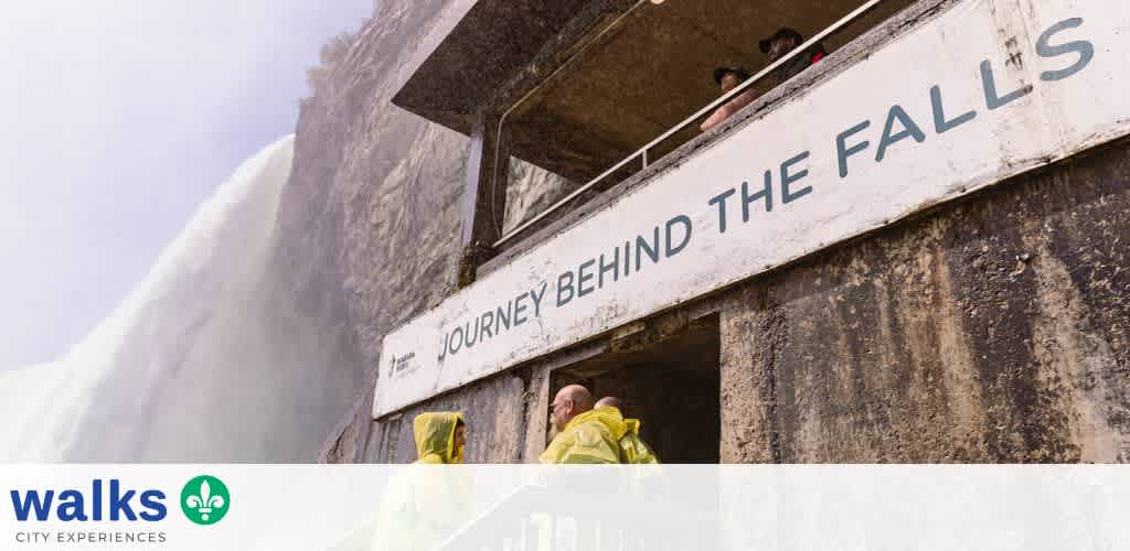 People standing on a viewing platform behind a large sign that reads journey behind the falls at Niagara Falls in July 2015