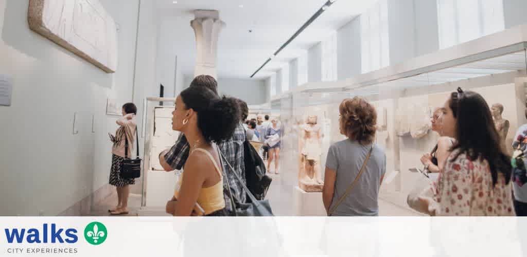 People viewing ancient sculptures and artworks in a bright museum gallery.