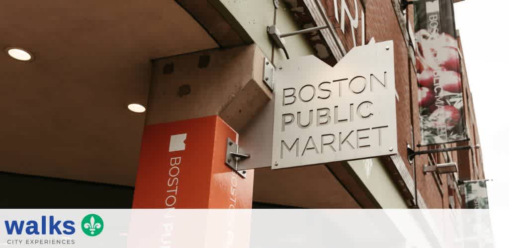 Sign for Boston Public Market mounted on building exterior, featuring modern font and a white background with black text.