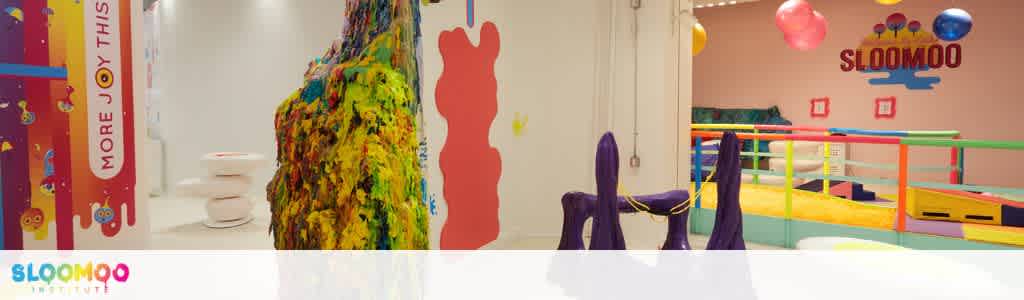 Colorful indoor play area with soft climbing structures, balance equipment, and vibrant decorations for children to enjoy.