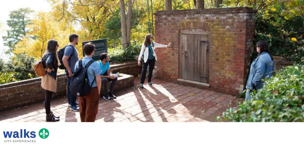 Group of children and a guide outdoors near a brick structure on a city walk tour