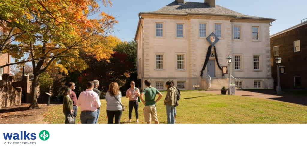 Group of people standing outdoors in front of a historic building with a large clock face decorated with a black ribbon for a memorial event