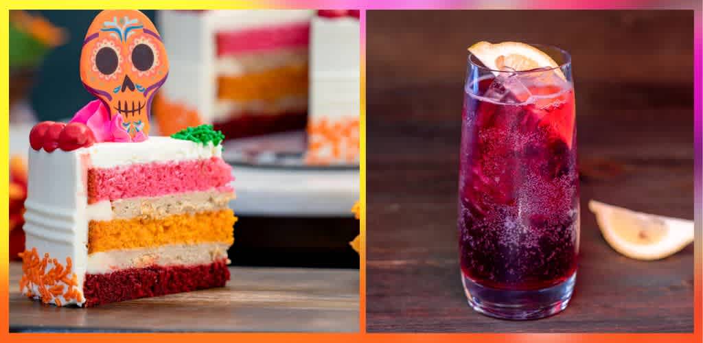 Colorful layered cake with a decorative sugar skull topper on a wooden surface, next to a glass of berry soda with lemon wedge on dark wood table.