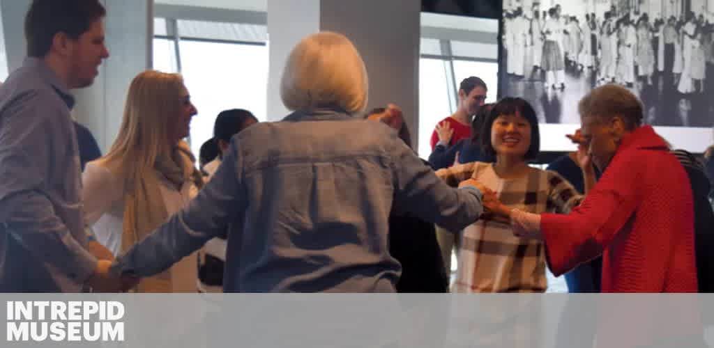People holding hands in a circle at the Intrepid Museum.