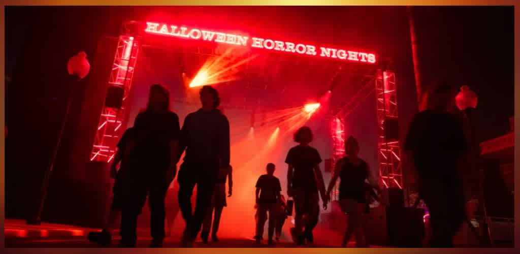People walking into a Halloween event with red lighting and a stage that reads Halloween Horror Nights