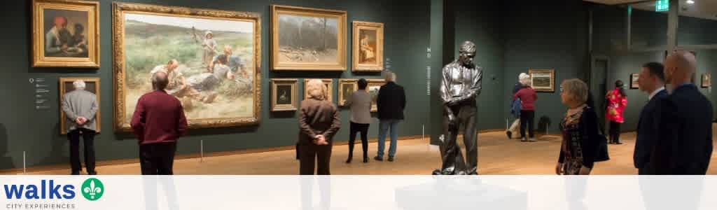 People viewing art on display in an art gallery with paintings on the wall and sculptures in the room