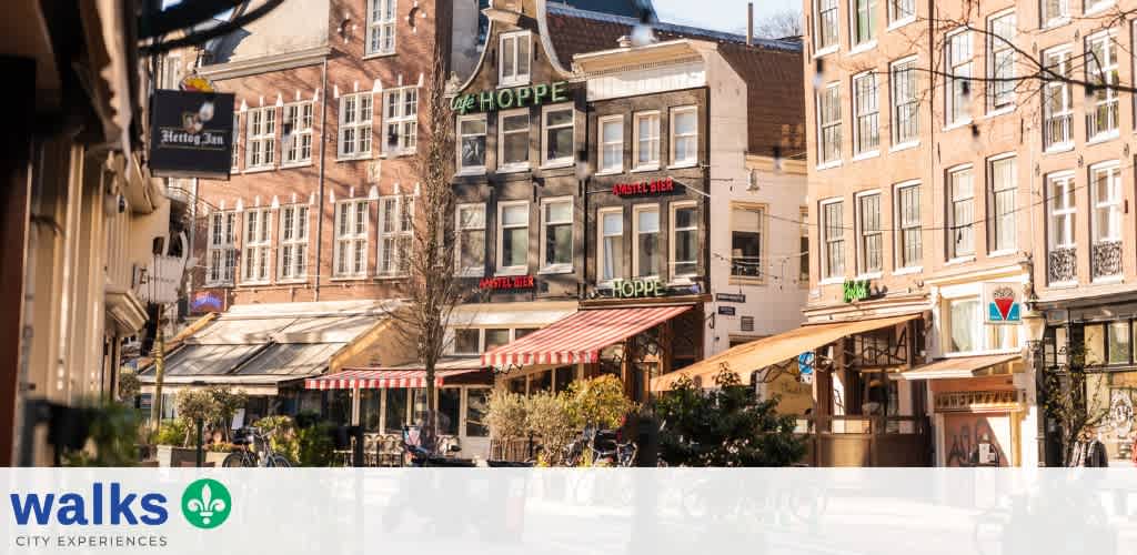 Street view of a lively urban area with cafes, shops, and outdoor seating on a sunny day
