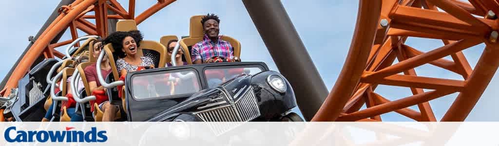 Group of excited people enjoying a roller coaster ride outdoors at an amusement park