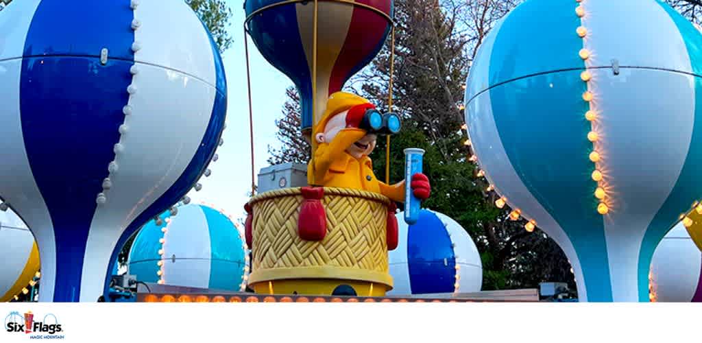 Colorful hot air balloon-shaped structures with a cartoon figure holding binoculars and a popsicle.