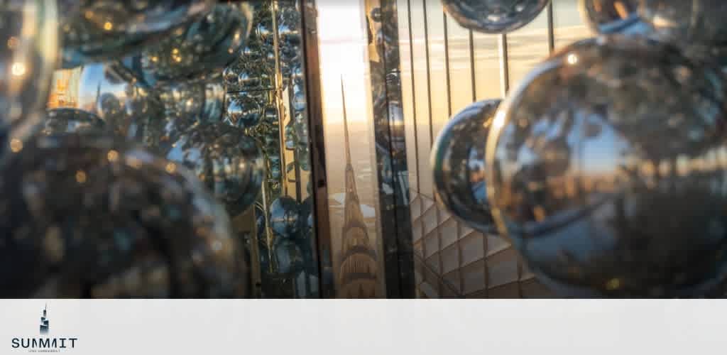 Reflective metallic spheres with a sunset in the background and a tall structure visible.