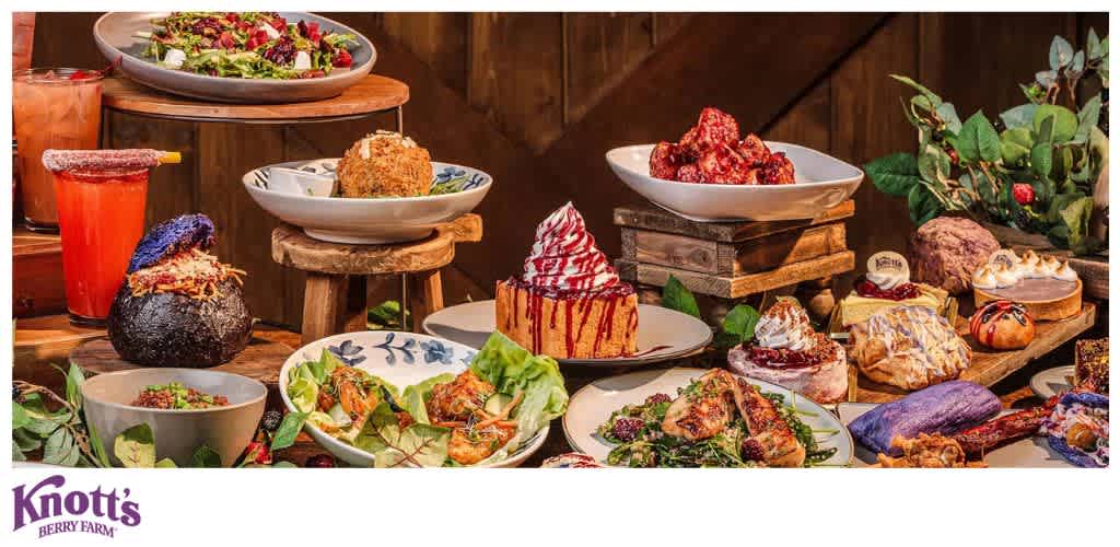 An array of colorful dishes and desserts displayed on a rustic wooden table with leafy decorations.