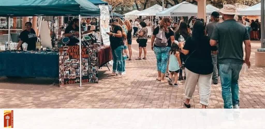 Outdoor market scene with vendor booths and people walking.