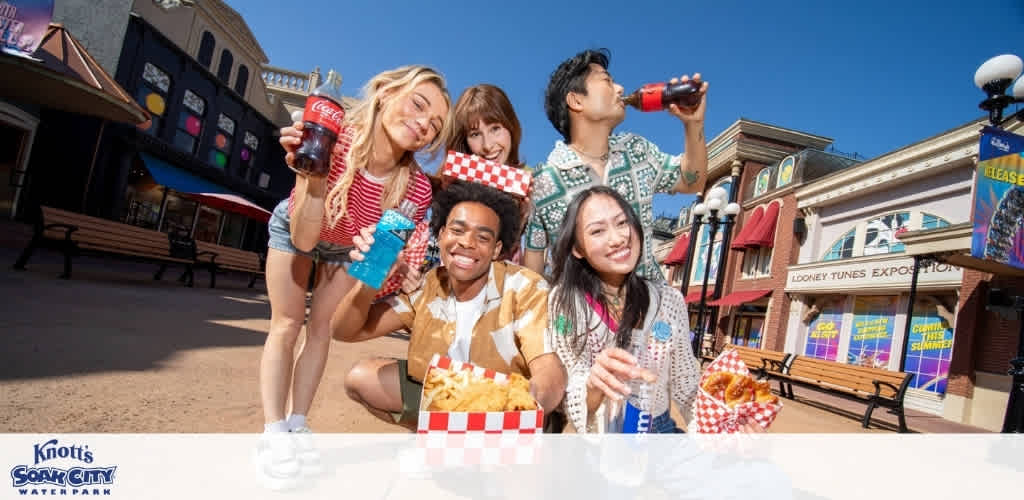 Group of diverse friends enjoying snacks and drinks outdoors at Knott's Soak City Water Park on a sunny day.