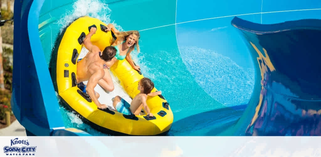 People enjoy a thrilling ride on a yellow inflatable raft descending a water slide at Knott's Soak City Water Park