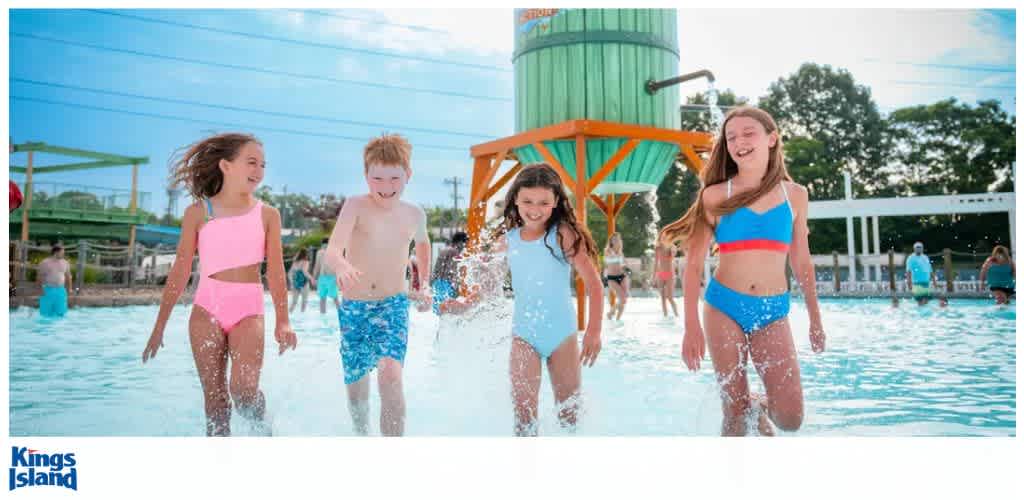 Children running and splashing in a water play area at an amusement park.