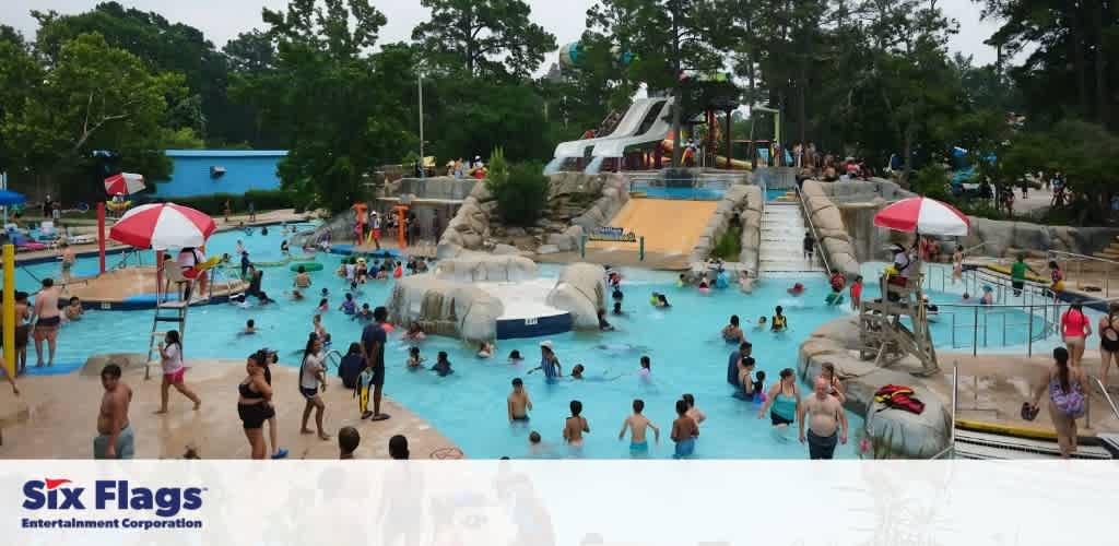 A busy water park with people enjoying a pool and water slides.