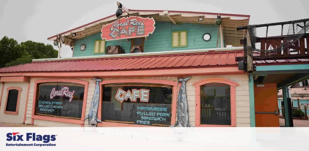 Front view of the Coral Reef Café, a colorful two-story building with neon signs and a shark decoration.