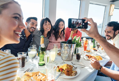 This image shows a joyful group of five friends enjoying a meal together at a well-lit, indoor venue with a window that suggests daytime lighting. They are gathered around a white table adorned with various dishes and drinks, indicating a festive atmosphere. On the left, a woman with a cheerful smile faces the camera, while a man on the right is holding a smartphone, taking a selfie of the group. The remaining three individuals turn towards the phone with bright smiles, actively participating in the selfie moment. Everyone appears to be engaged and savoring their time together.

GreatWorkPerks.com is dedicated to ensuring you experience moments just like these without breaking the bank. We pride ourselves on offering the lowest prices on tickets, so you can enjoy the savings while creating unforgettable memories.