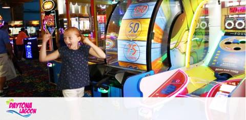 Child excited in arcade with colorful game machines. "Daytona Lagoon" logo visible.