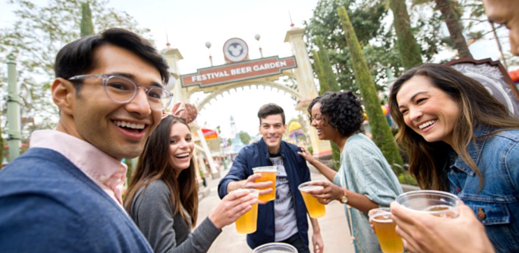 Group of friends smiling and holding beers at the Festival Beer Garden outdoor event