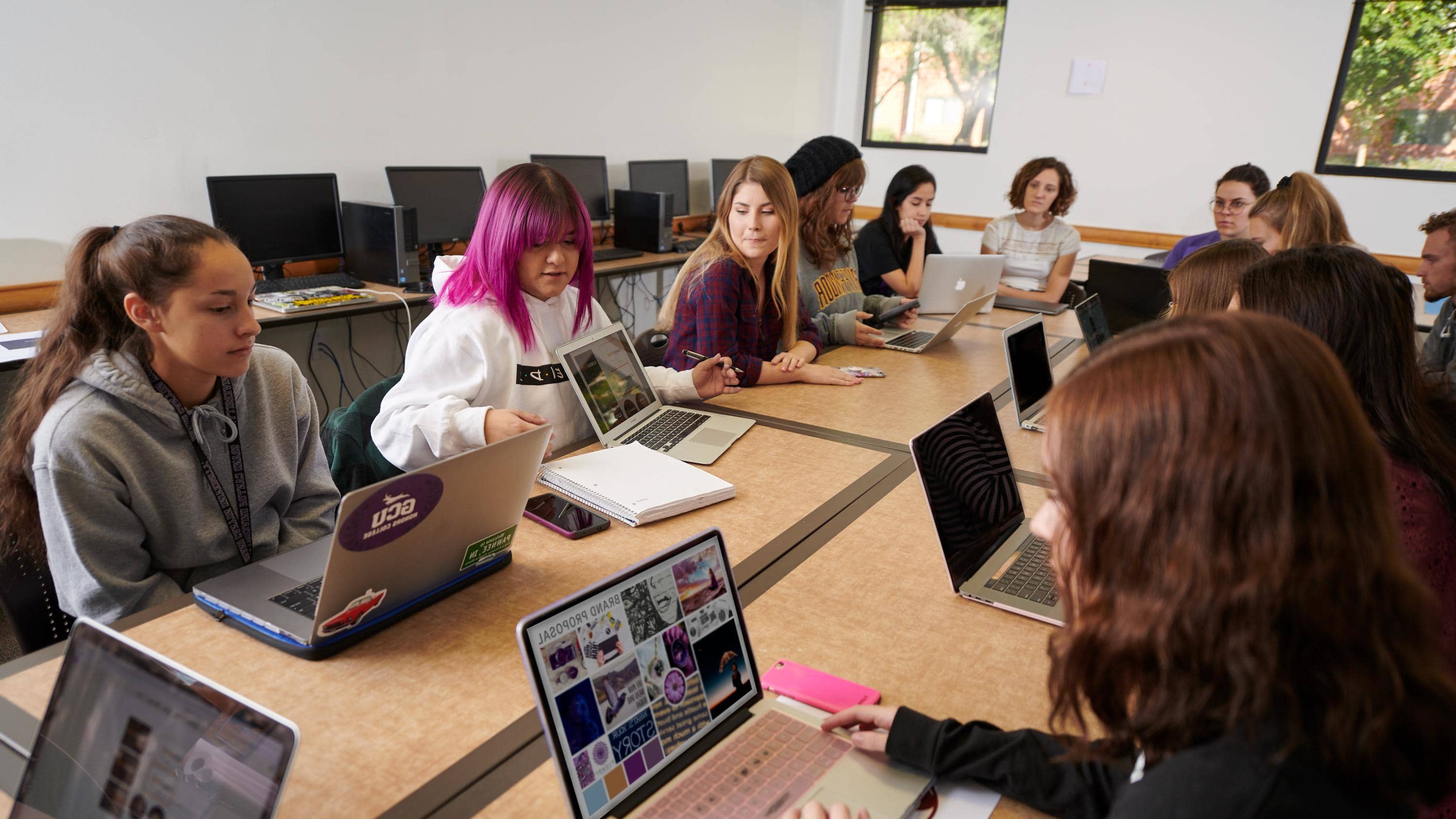 Group of digital media degree students working on laptops in GCU classroom