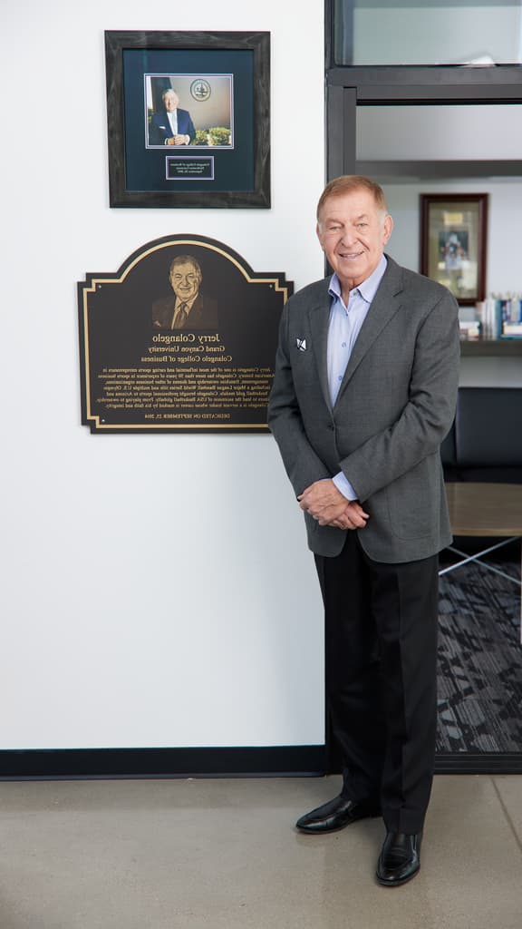 Jerry Colangelo posing by a Colangelo College of 业务 plaque