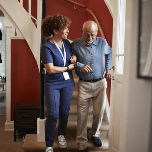 成熟的女护士和老人在家里的台阶上散步