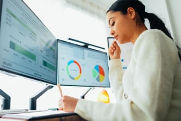 Woman looking at financial charts on computer screens