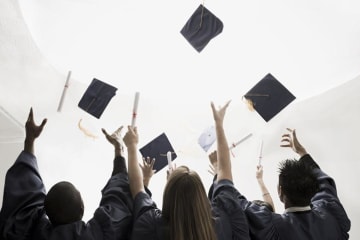 Three graduates throwing up their motarboards