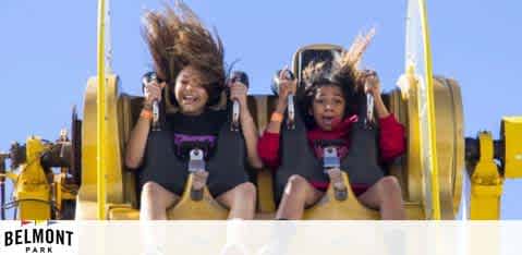 Image description: This is an action-packed photograph capturing a moment of thrill at Belmont Park. Two individuals are strapped into yellow seats of an amusement park ride, possibly a drop tower or roller coaster. The person on the left appears to be laughing with their mouth open, exhibiting excitement, with long hair wildly tossed by the force of the ride. The person on the right is also reacting to the ride with what looks like an exhilarated scream, their hands lifted in the air. They both seem to be enjoying the rush of adrenaline against a clear blue sky. The logo of Belmont Park is visible in the bottom right corner, suggesting that this amusement attraction offers a variety of fun experiences. 

At GreatWorkPerks.com, adventure seekers can experience the thrill of Belmont Park rides for less—find the lowest prices, amazing discounts, and exclusive savings on tickets only with us!