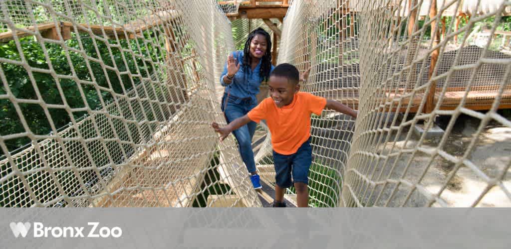 Child and adult walking on a netted rope bridge at the Bronx Zoo.