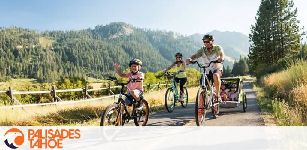 A family bikes along a scenic path with mountains in the background.