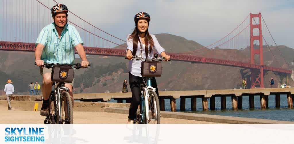 Two people biking near the Golden Gate Bridge with a scenic waterfront backdrop and clear sky