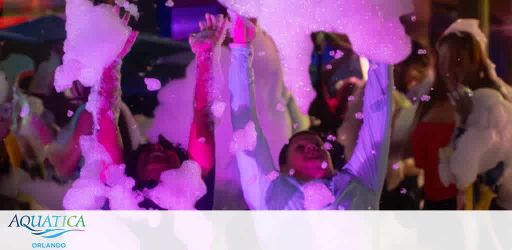 People at a colorful foam party with arms raised.