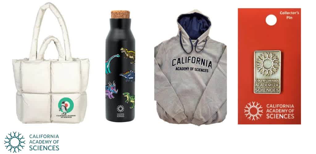 Four items from the California Academy of Sciences: a white tote bag, a black bottle with dinosaur illustrations, a gray hoodie, and a collector's pin on an orange card.