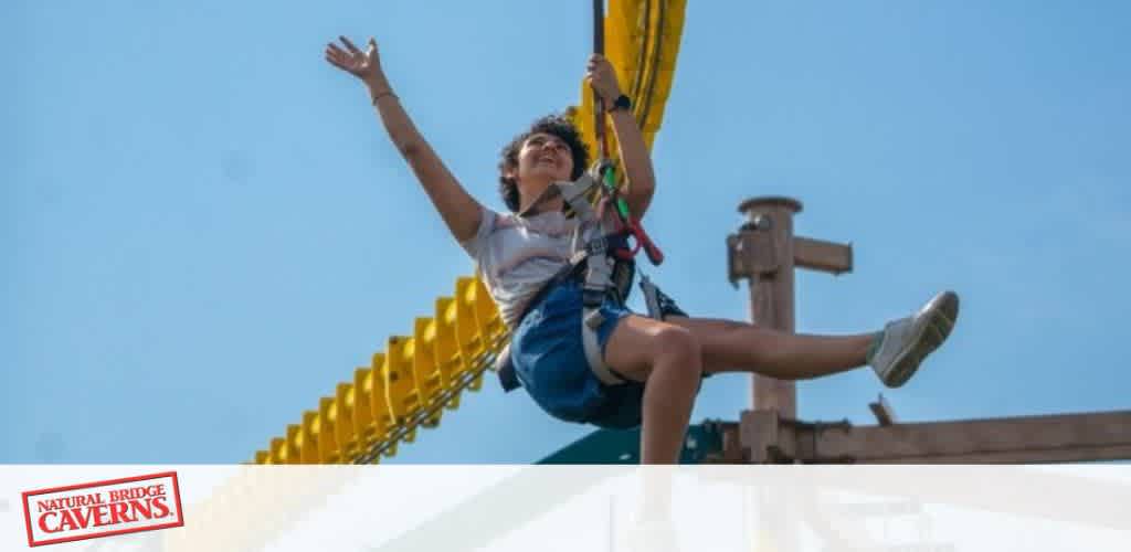 Person zip-lining against a clear blue sky, with a