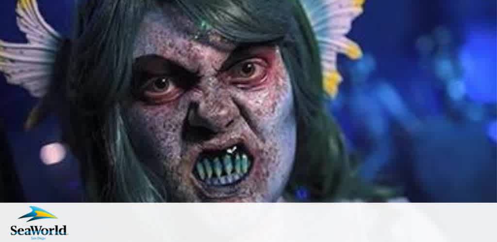Close-up of a person made up to look like a sea creature with green hair and sharp teeth.