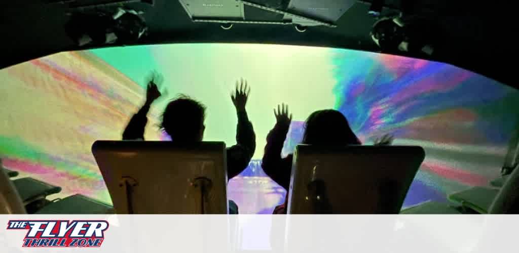 Description: This image captures the excitement of an immersive experience, with two individuals seated in a motion ride simulator, their arms raised in joy. They are silhouetted against a large, curved projection screen filling their view with vibrant, swirling patterns of light in shades of blue, green, pink, and purple. The dome-shaped screen creates a sense of depth and movement, enhancing the thrilling sensation of the ride. Above them, part of the ride's structure is visible, with lights and mechanical components contributing to the overall high-tech atmosphere. The logo "THE FLYER—THRILL ZONE" is positioned in the lower right corner, indicating the brand or attraction.
At GreatWorkPerks.com, we are committed to bringing you the highest level of excitement at the lowest prices. Dive into a world of thrills and secure your tickets with us, ensuring you get the best savings on your next adventure.