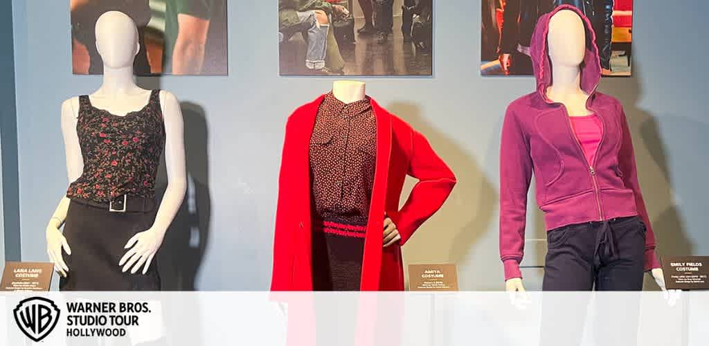 Three mannequins in outfits are displayed against a blue wall with photos above.