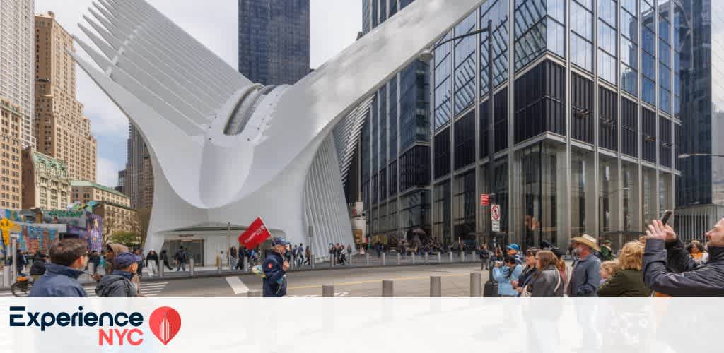 The image showcases a bustling city scene in front of a modern architectural structure with curved, wing-like features. People are gathered around, enjoying the vibrant urban atmosphere. Tall skyscrapers surround the area, highlighting a blend of futuristic design and city life. The site exudes energy, culture, and dynamic movement, embodying the essence of exploration and experience in an iconic city setting.