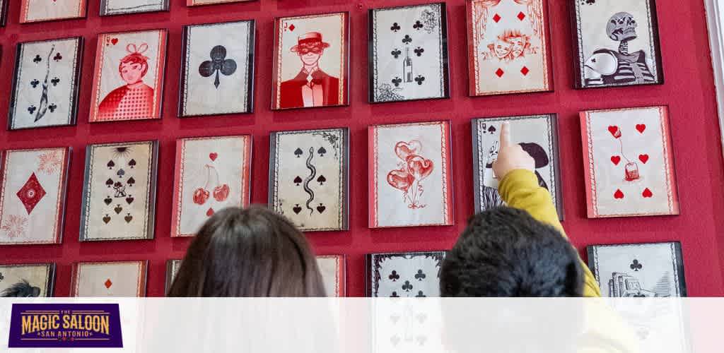 Two children looking at a wall of playing cards with a red background and a Magic Saloon logo at the bottom.